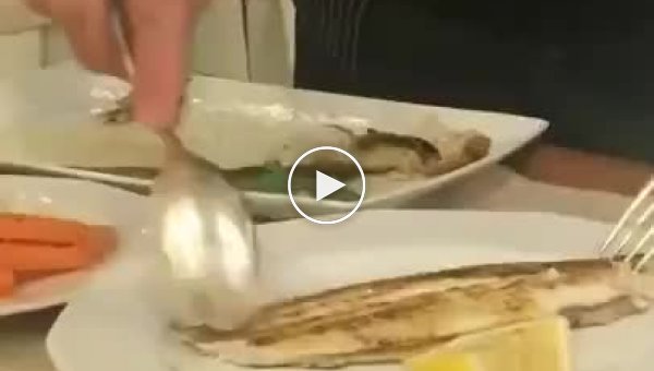 Официант убирает кости из рыбы